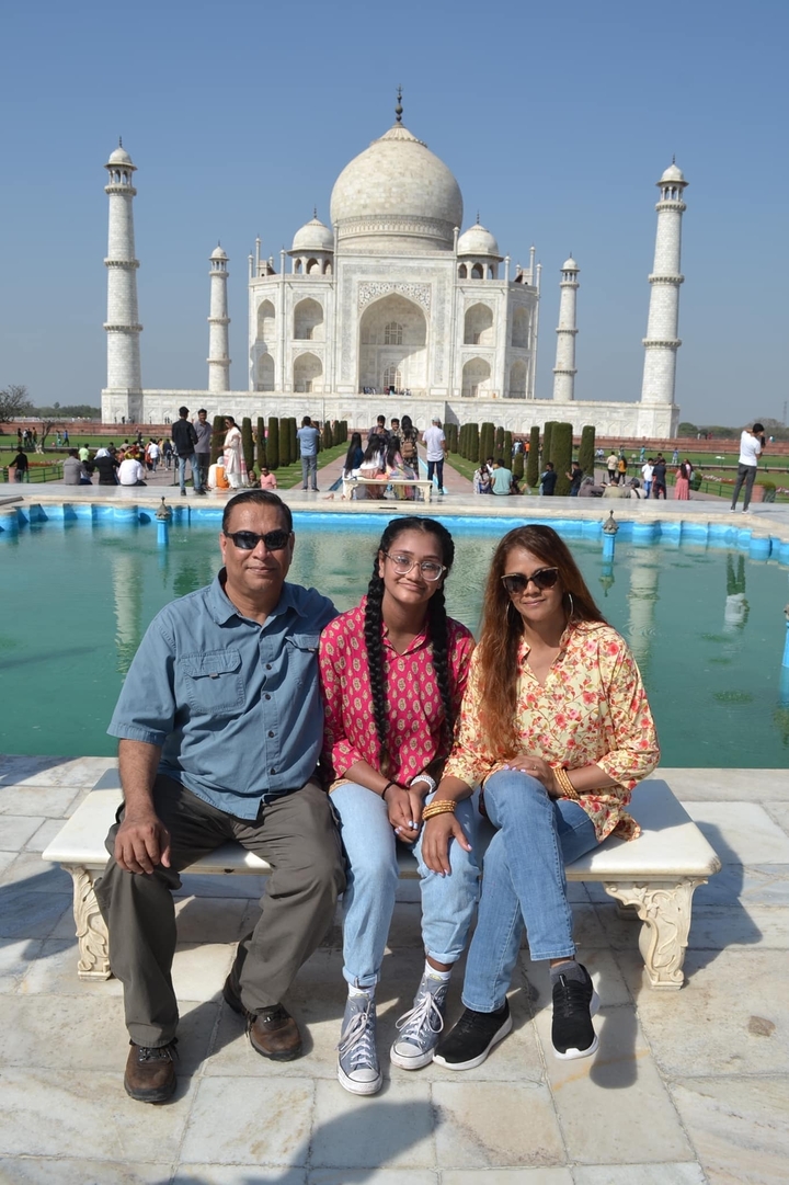 Family posing in front of a pool with the Taj Mahal in the background