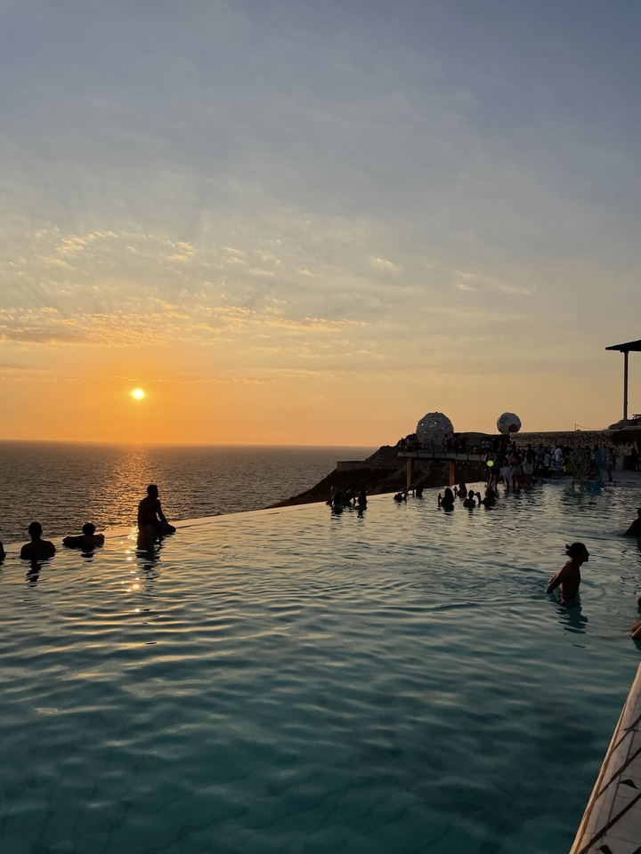 Infinity pool with people enjoying a sunset view