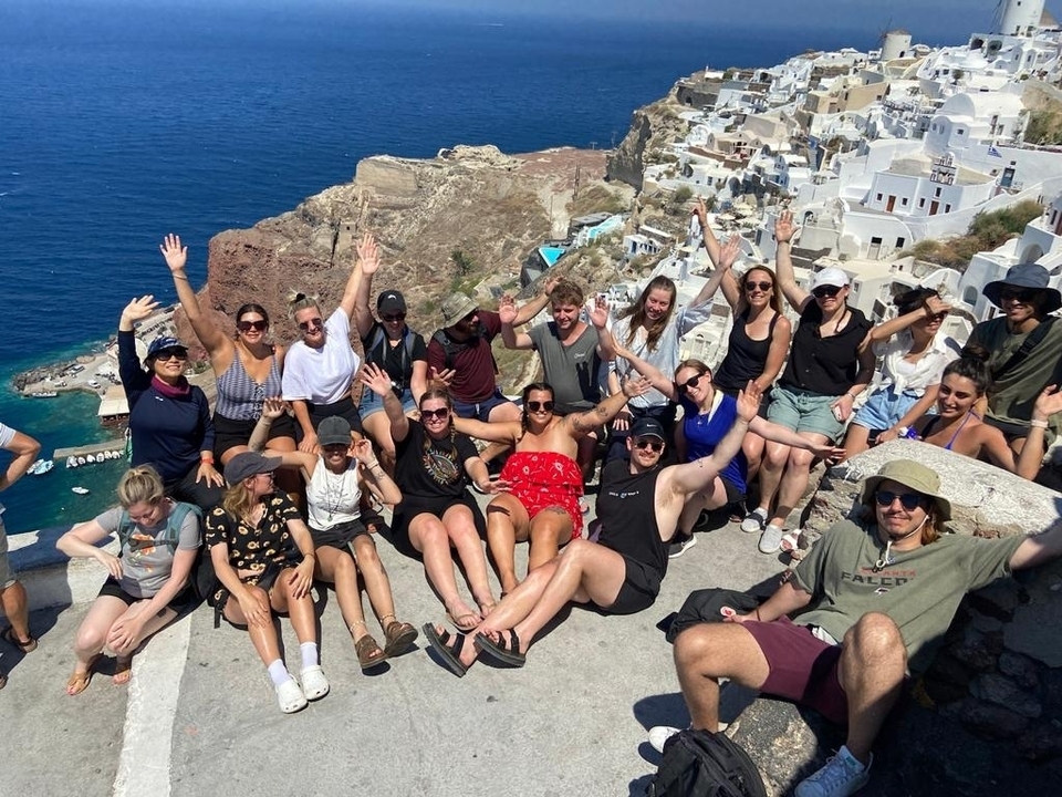 Large group of people posing with a view of a coastal town