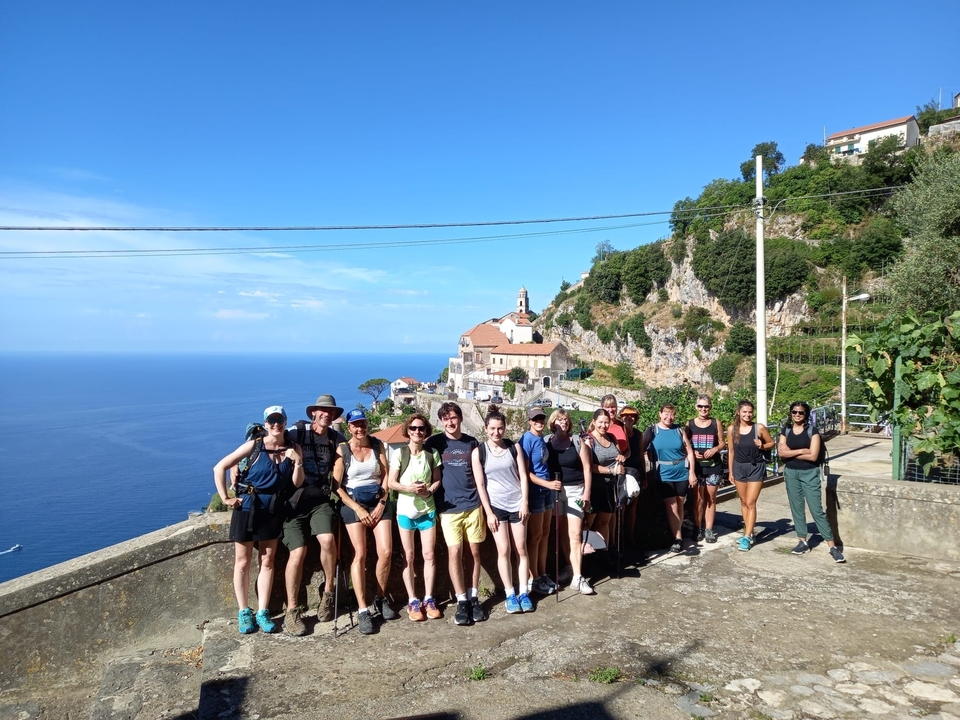 Group of people posing with a scenic church and coastline