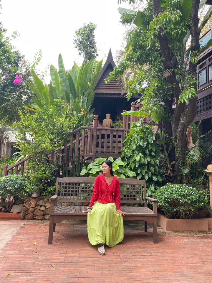 Woman sitting on a bench in a lush garden