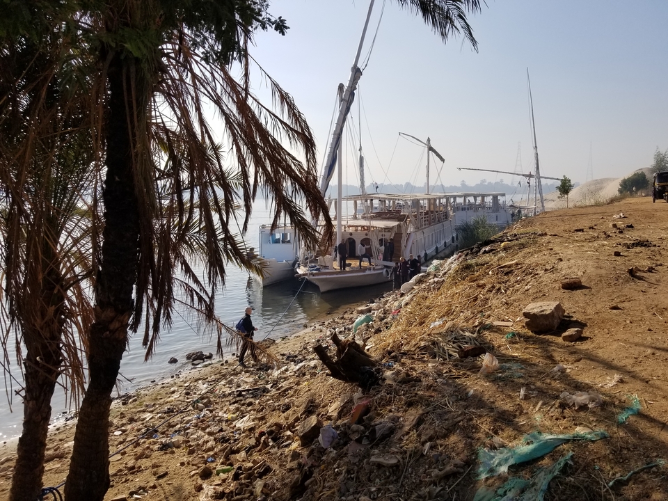Riverbank with a docked boat and people walking.