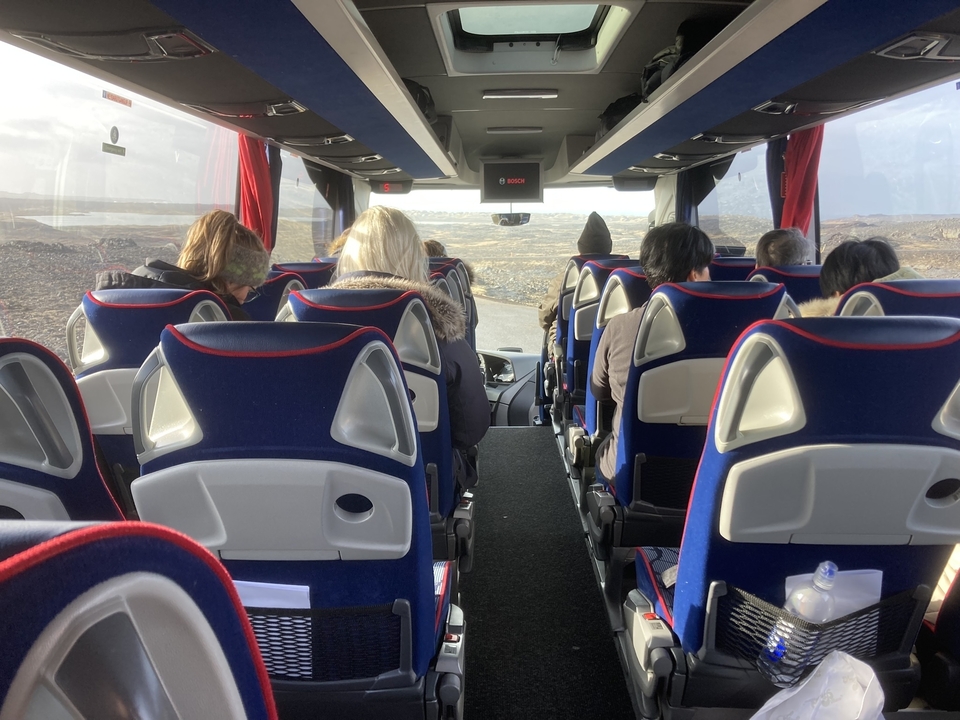 Passengers seated inside a tour bus with scenic views outside.