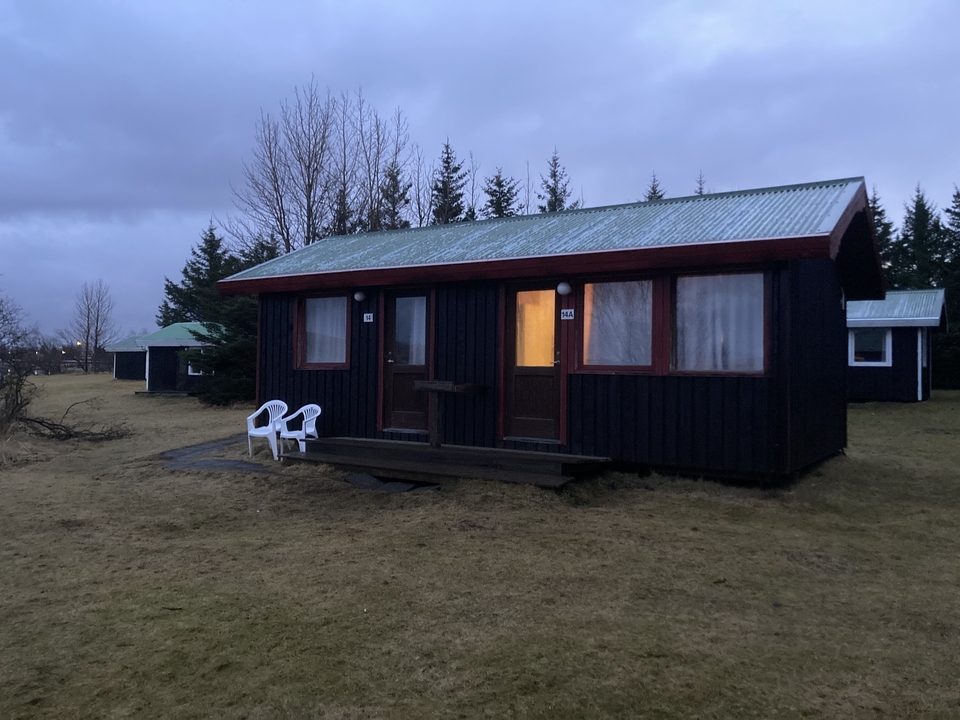 Cozy cabin in a forested area during dusk.
