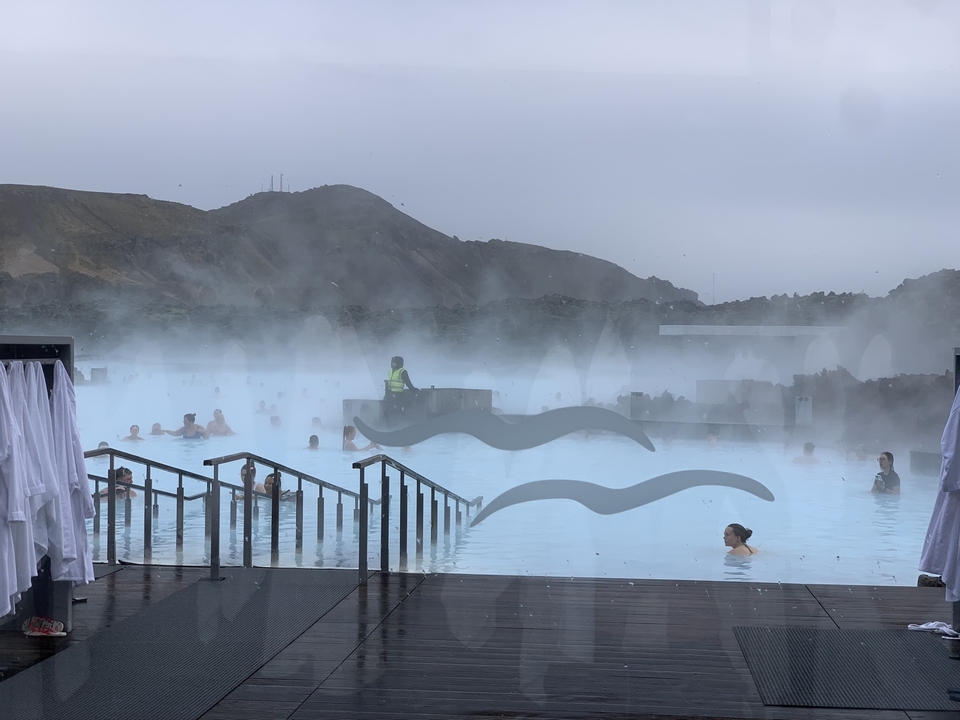 People enjoying Blue Lagoon geothermal spa with mist rising.