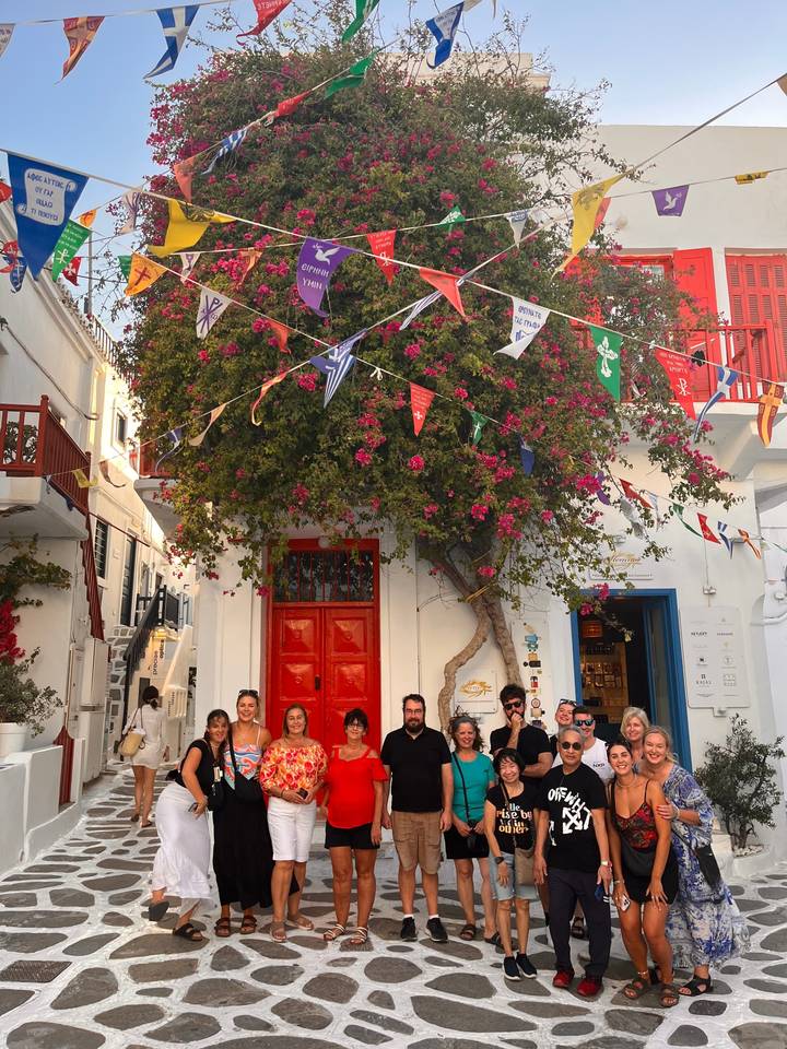 A group of tourists standing under a decorated tree and colorful flags.