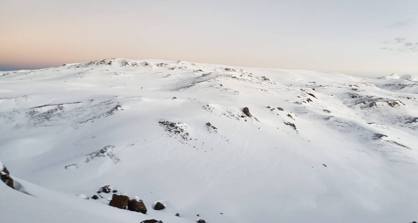 Vaste paysage enneigé sous un ciel légèrement rosé.