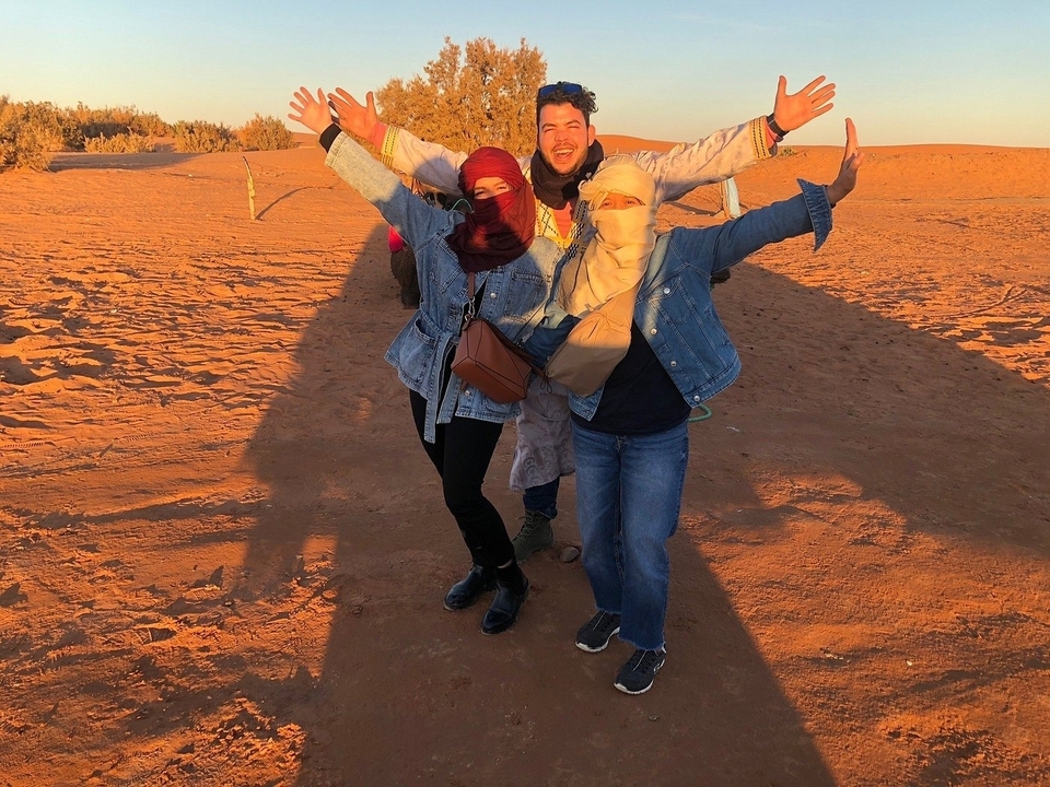 Three people dressed warmly, posing funnily in the desert.