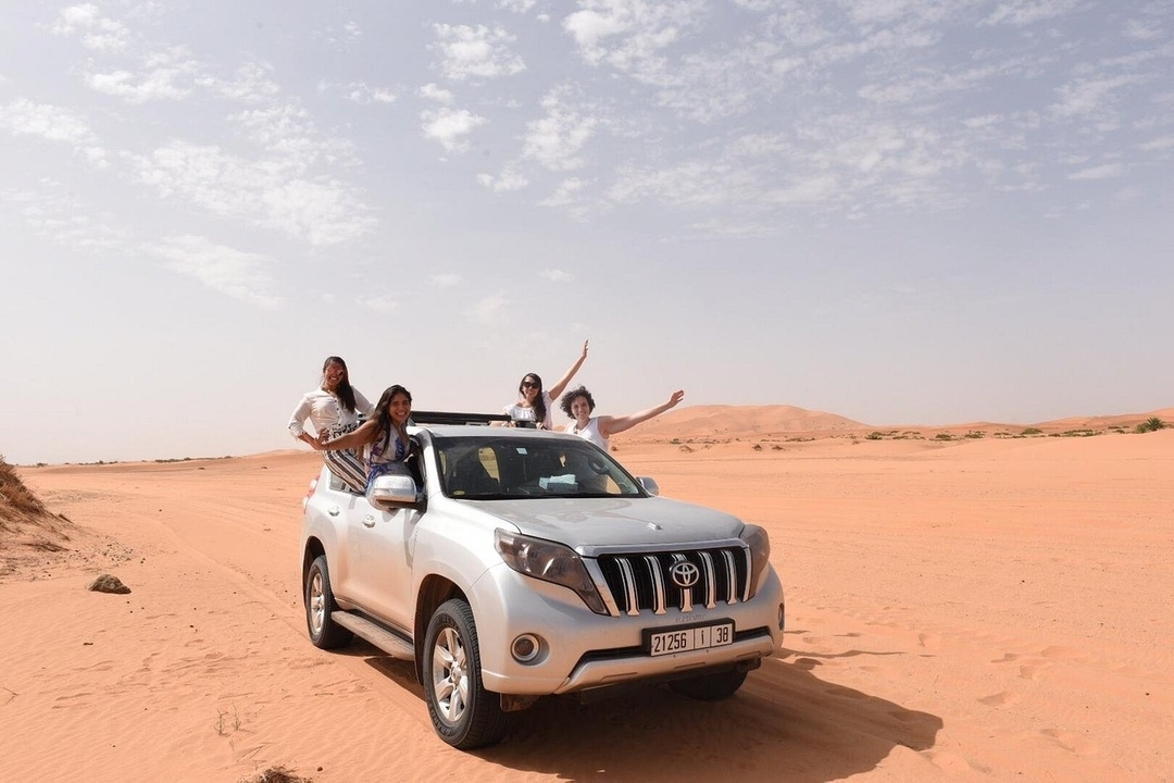 A group of people on a 4x4 vehicle in the desert.