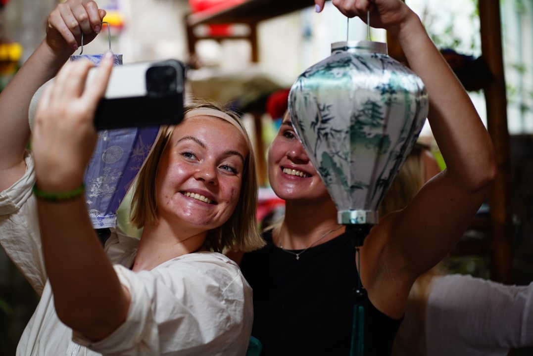 Two people taking a selfie while crafting paper lanterns.
