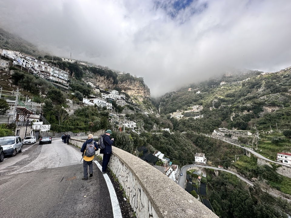 Scenic hillside village view with roads and overcast sky.