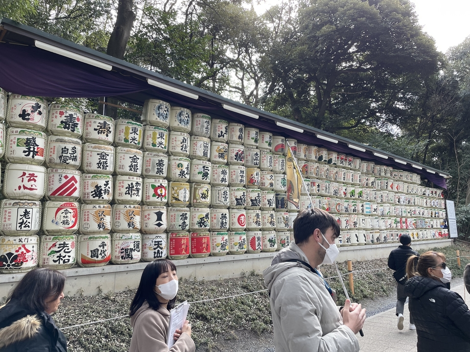 Colorful sake barrel wall with people taking photos.