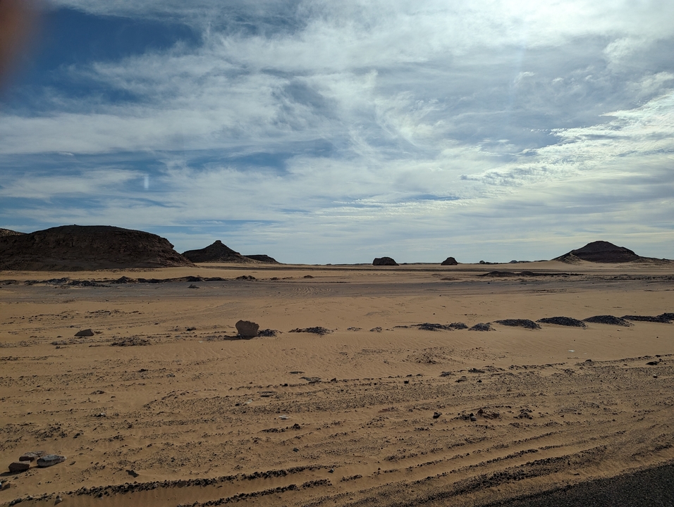 Desert landscape with sandy terrain and distant hills.