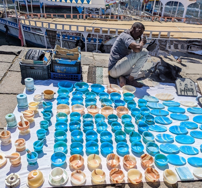 Vendor selling blue ceramic bowls on a sidewalk.