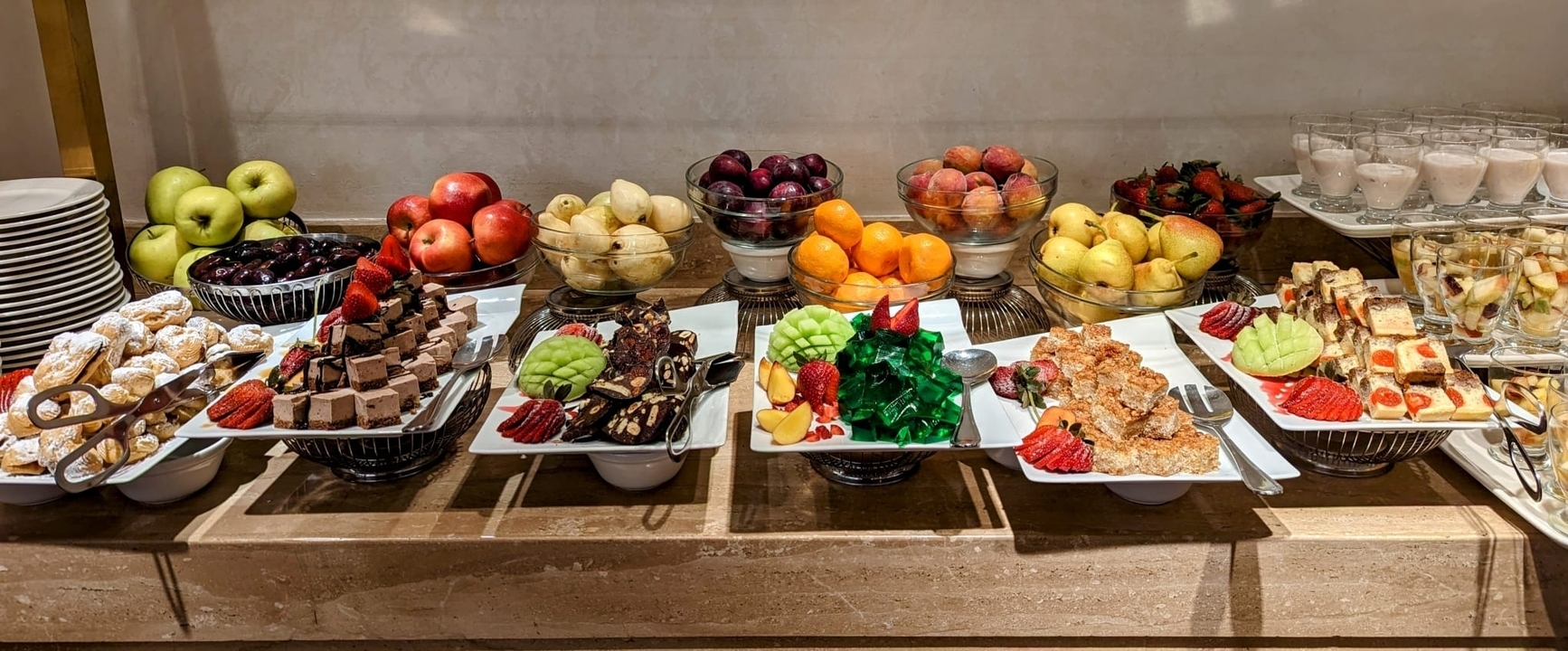 Assorted fruits and desserts on a buffet table.