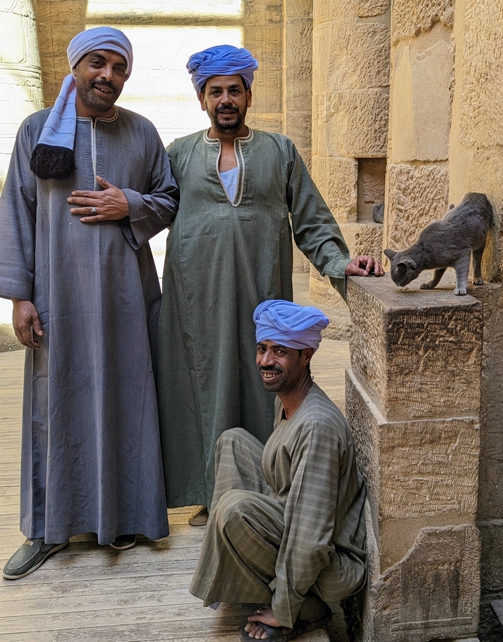 People dressed in traditional clothing beside a cat.