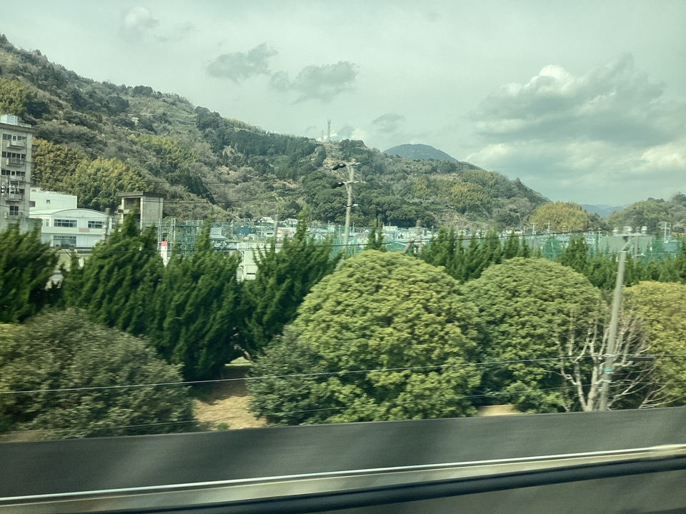 A train's window view of mountainous scenery with buildings.