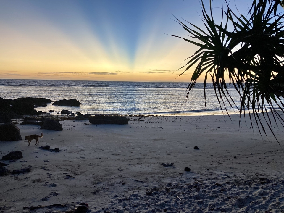 A serene sunset on a sandy beach with the silhouette of an island.