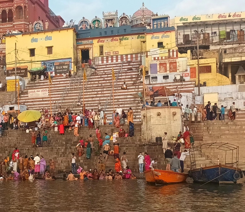 Foule se rassemblant sur les marches du bord de rivière avec des bâtiments colorés.