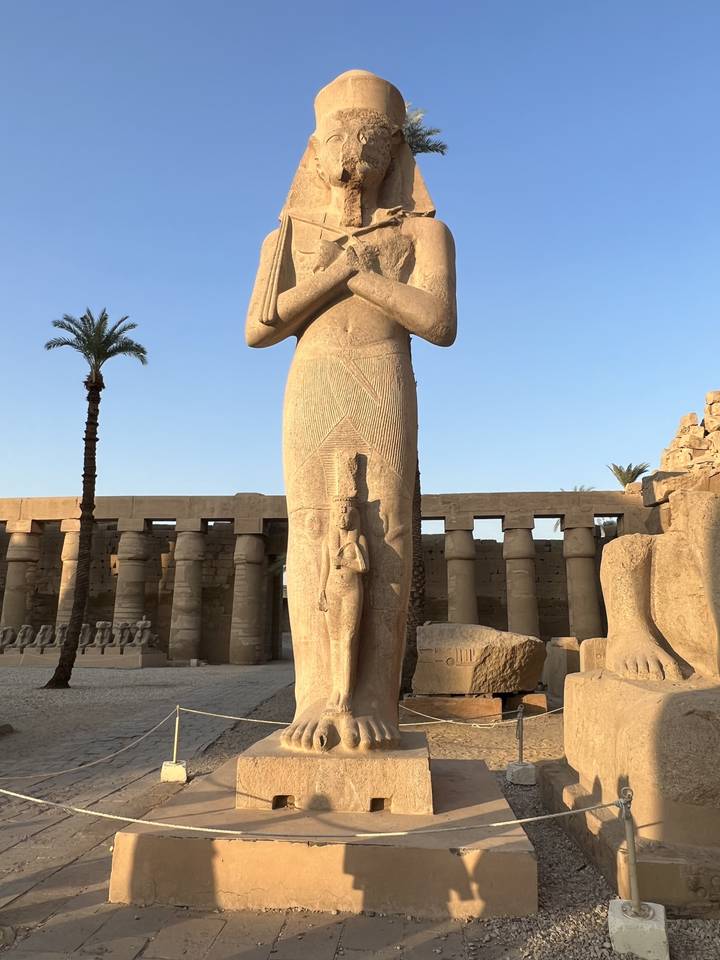 Statue égyptienne antique dans un site archéologique extérieur.