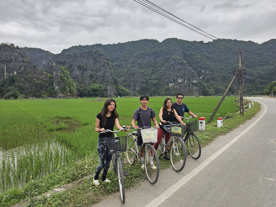 Groupe de personnes debout avec des vélos dans une campagne luxuriante avec des collines calcaires.