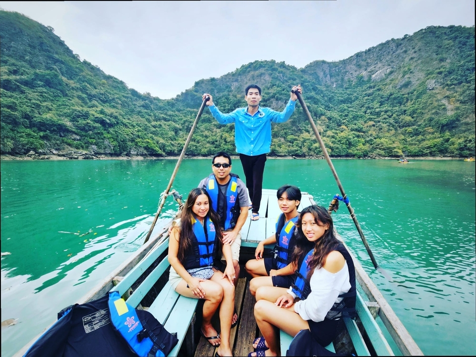 Groupe de personnes profitant d'une promenade en bateau sur des eaux d'un vert éclatant avec des collines luxuriantes.