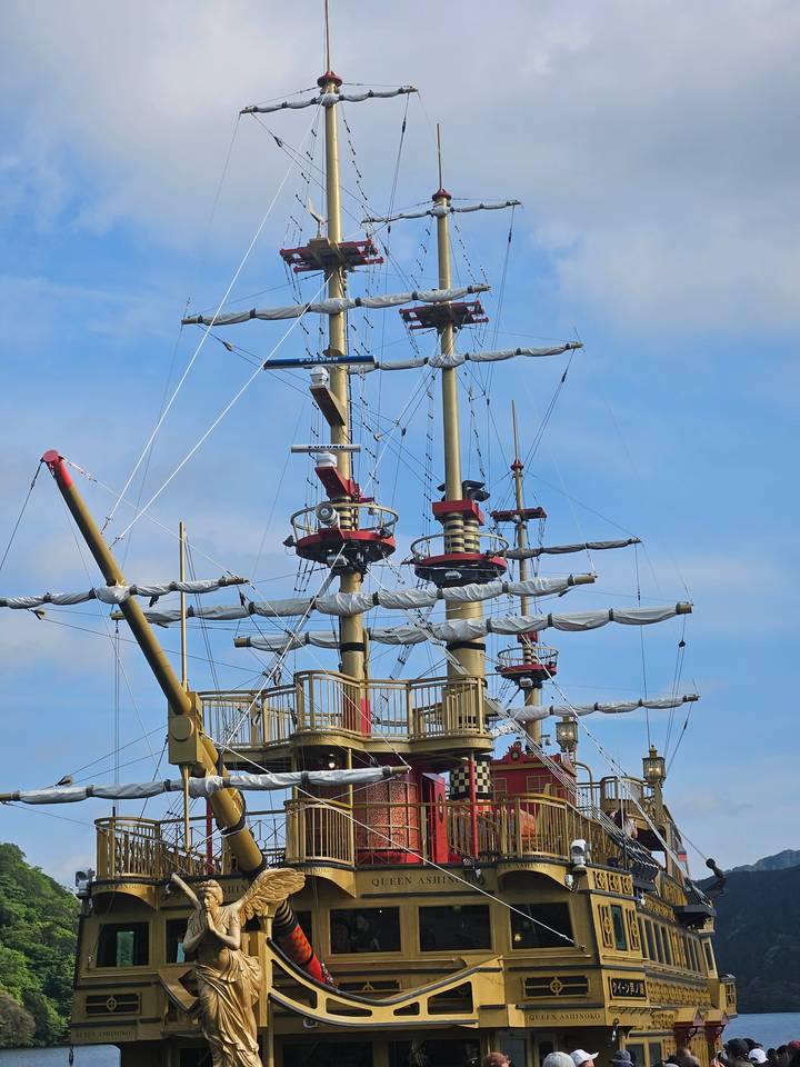 Pirate ship with raised sails at a dock.