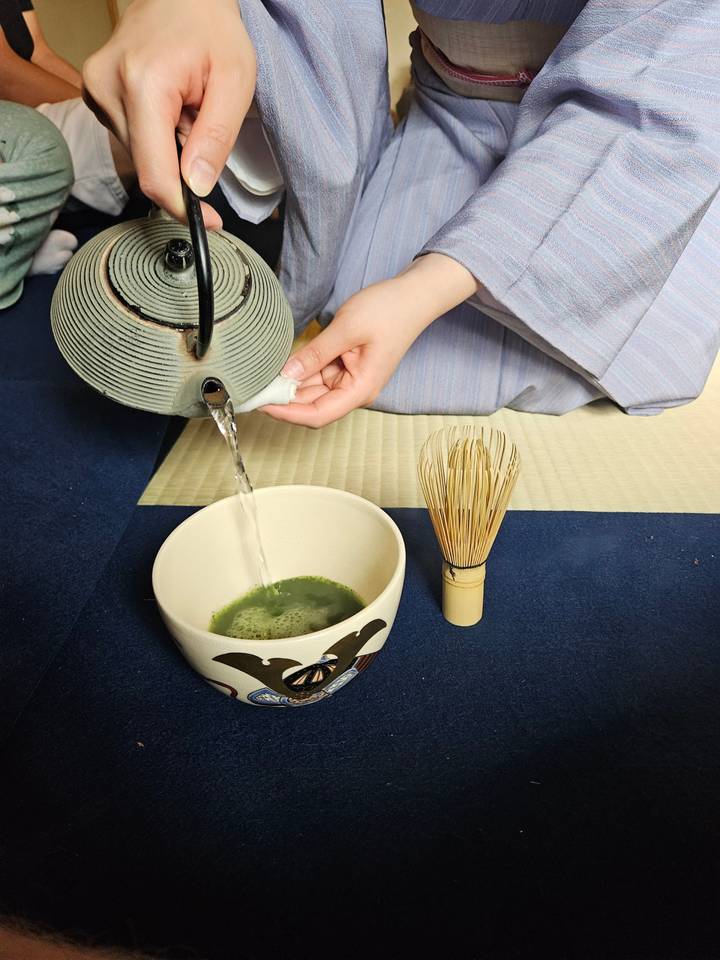 Person preparing macha tea in a traditional tea ceremony.