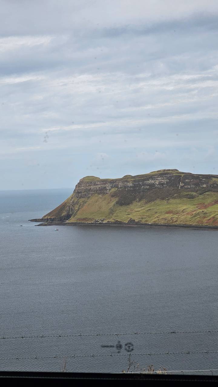 Coastline view with green hills and a wide expanse of water.