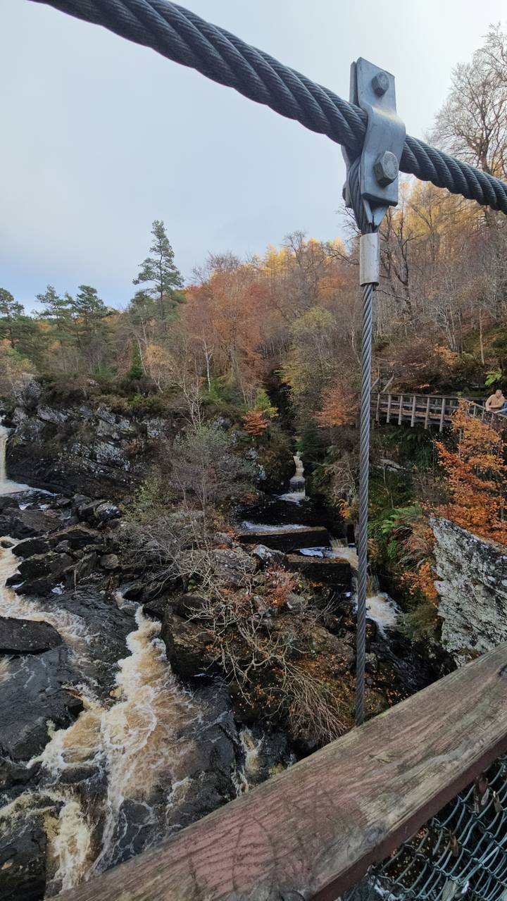 Suspension bridge over a waterfall with autumn colors.