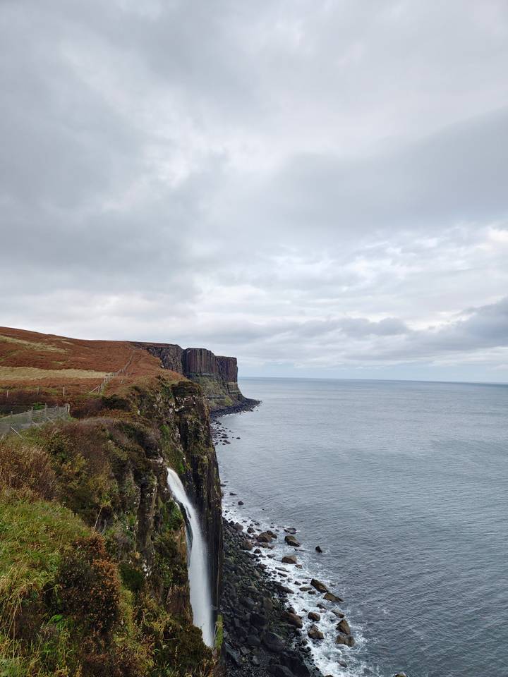 Coastal waterfall with rocky cliffs.