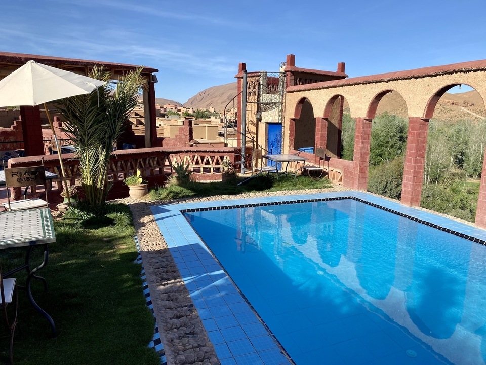 Poolside area with tables and lounge chairs offering a mountain view.