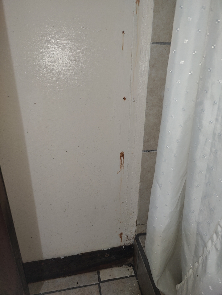 Wall with visible rust stains next to a curtain.