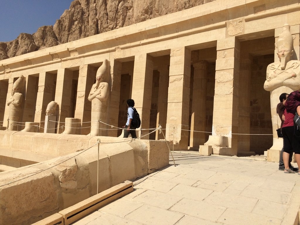 Des personnes visitant un temple égyptien antique avec des statues.