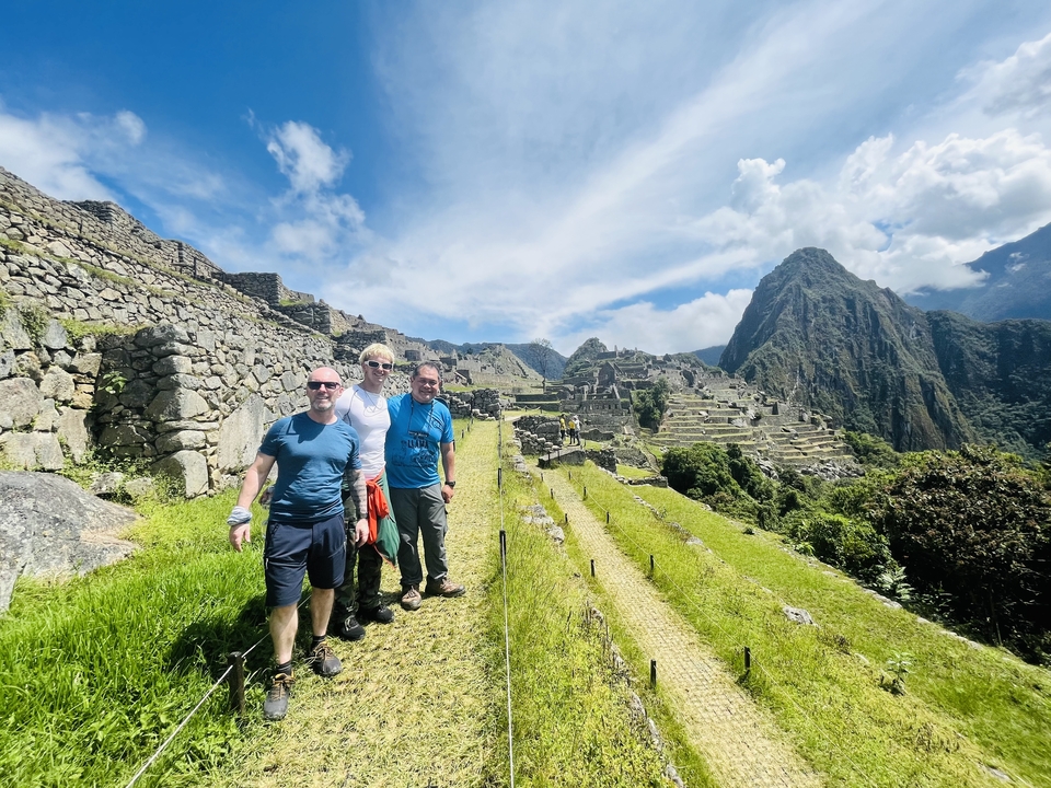 Three people posing with Machu Picchu in the background.