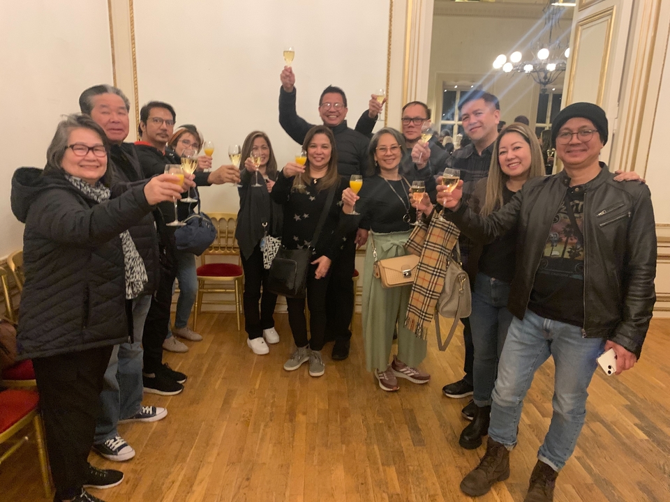 A group of people raising glasses together in a room.
