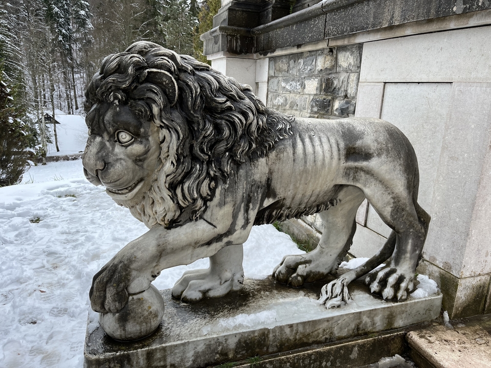 Stone statue of a lion in snowy surroundings.
