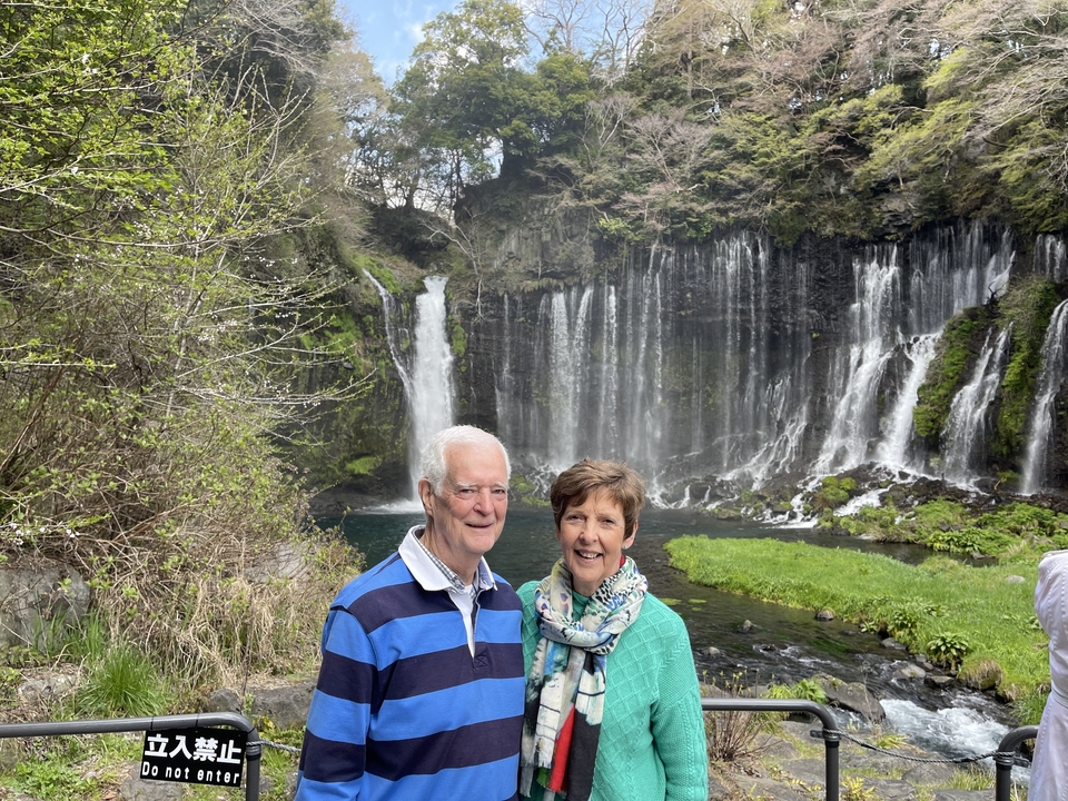 Couple âgé debout devant une cascade pittoresque.