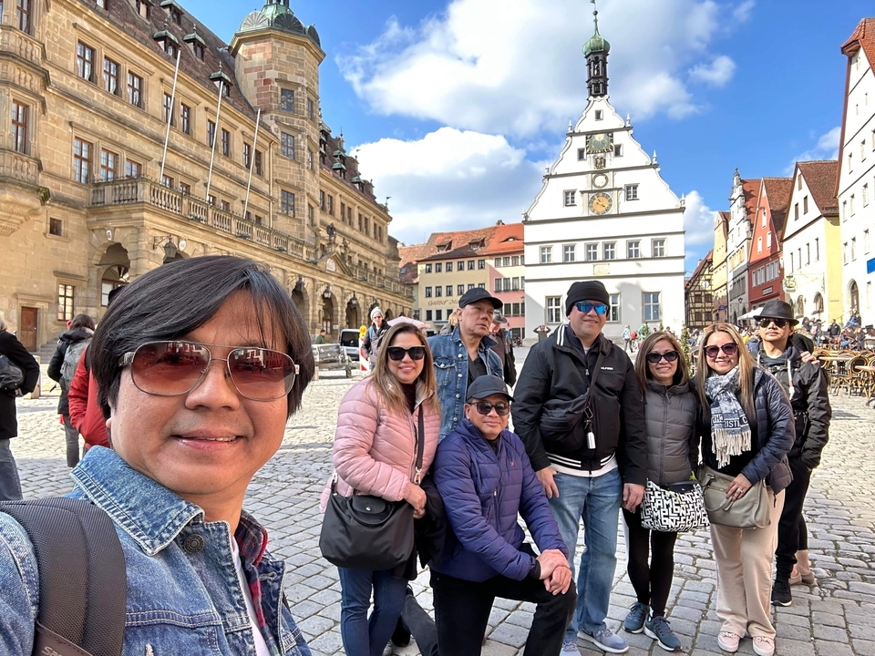 Tourist group posing in a historic town square with old buildings.