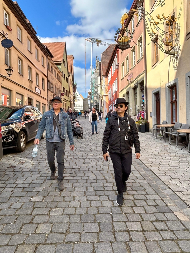 People walking down a cobblestone street lined with colorful buildings.