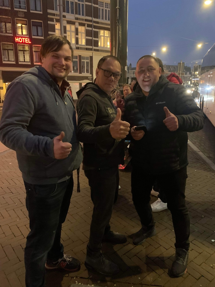 Group of people posing at night with thumbs up.