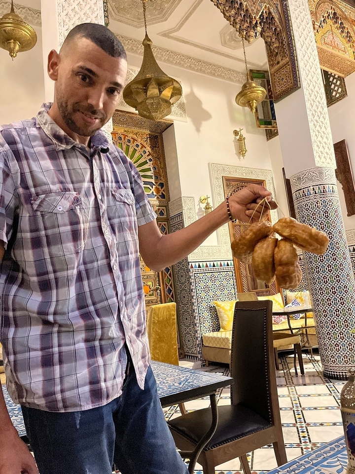 Person holding traditional Moroccan bread in a decorated room.