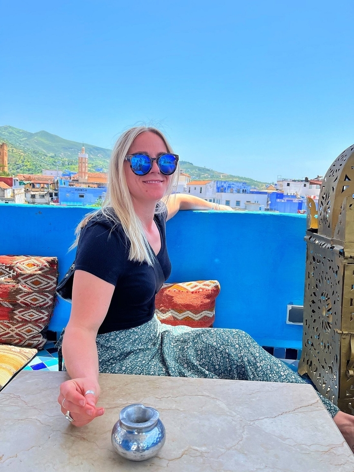 Person sitting on a rooftop terrace in a blue city.