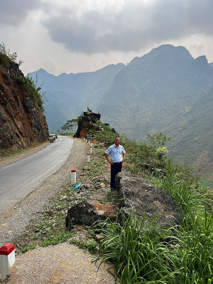 Person standing on a rock next to a scenic road.