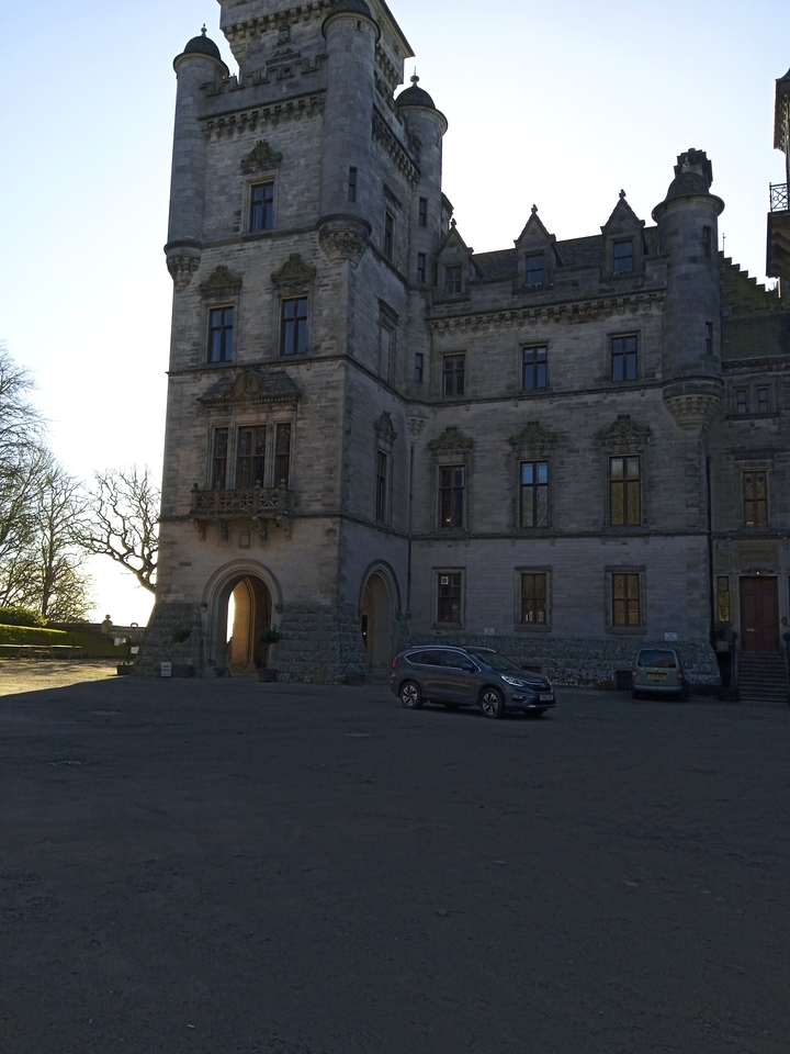 Stone building with parked cars.