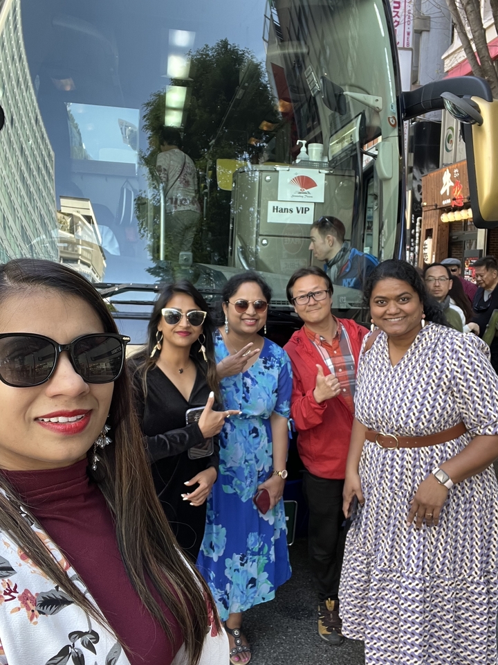 Group of people posing in front of a tour bus.