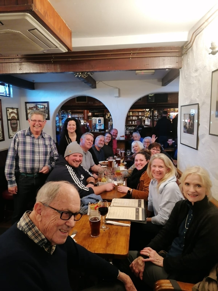 Groupe de personnes savourant des boissons à l'intérieur d'un pub.