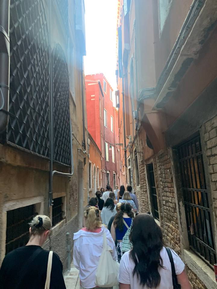 People walking down a narrow historic street.