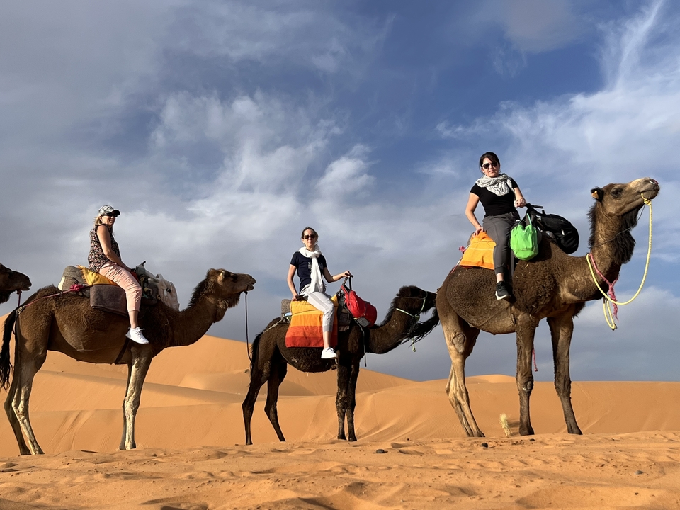 People riding camels in the desert.