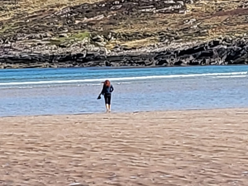Femme marchant seule sur la plage avec un rivage rocheux